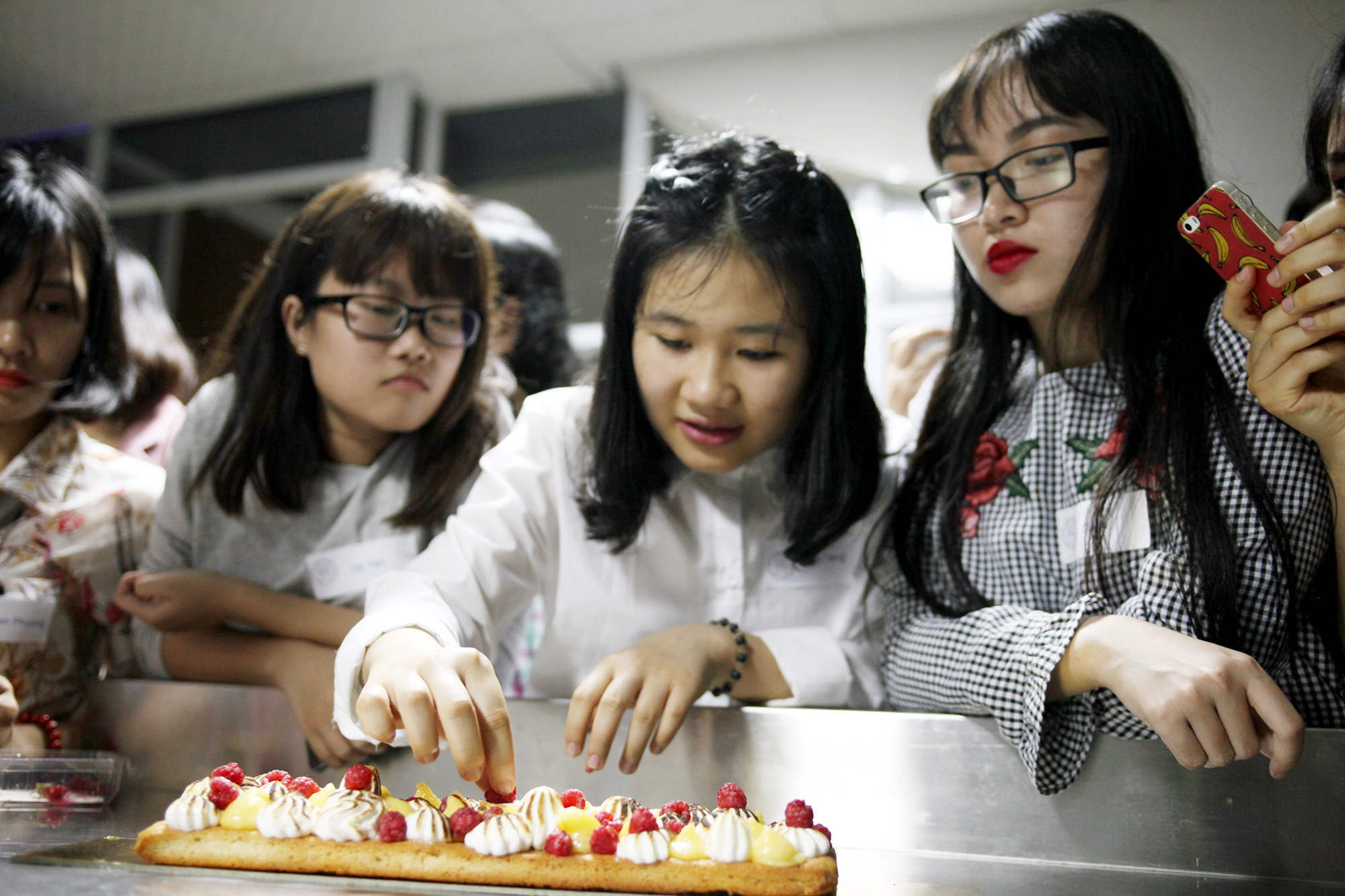 Các bạn trẻ tham dự Gout de France tự tay trang trí cho món bánh vừa làm. (Ảnh: Doãn Đức/Vietnam+)