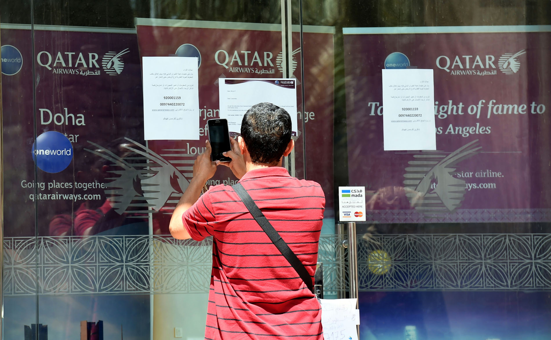 Một người đứng chụp ảnh bảng thông báo trước văn phòng hãng Qatar Airways ở Riyadh, Saudi Arabia. Thông báo nói rằng văn phòng này bị đóng cửa theo yêu cầu của Cơ quan hàng không dân dụng Saudi. (Nguồn: AFP)