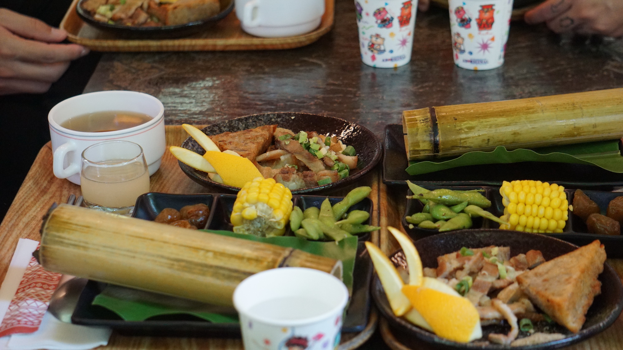 Du khách thưởng thức bữa trưa đậm chất miền sơn cước tại Làng Cửu tộc gồm các món chính như rượu hoa quả, ngô, đậu luộc, thịt lợn quay ba chỉ. (Ảnh: Trần Long/Vietnam+)