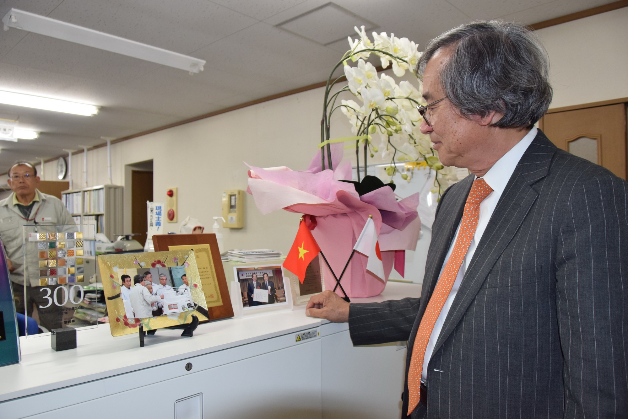 Ông Trần Ngọc Phúc giới thiệu bức ảnh kỷ niệm ghi lại ngày Nhà vua Nhật Bản đến thăm Metran. (Nguồn: Vietnam+)