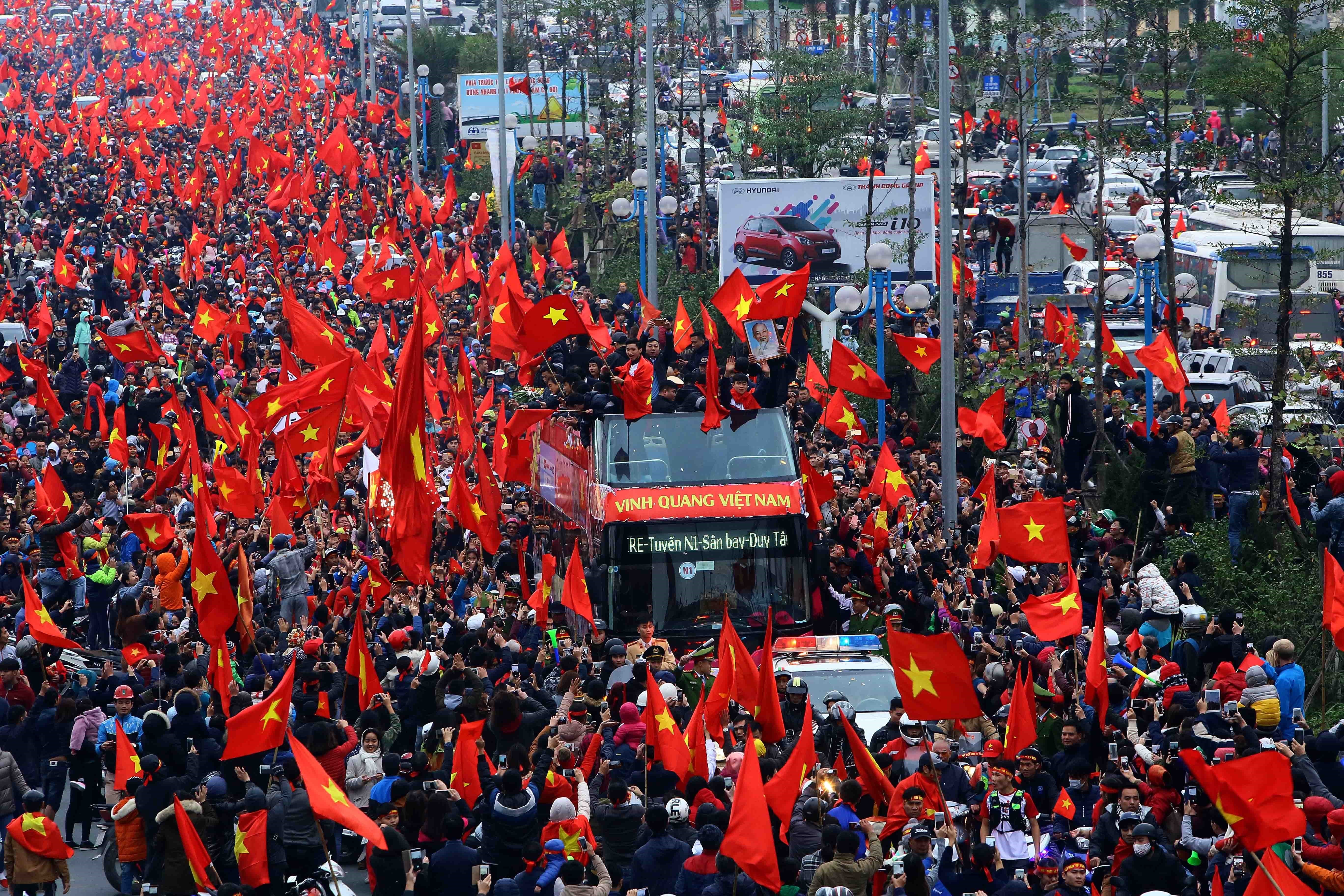 Người hâm mộ với băngrôn, cờ và hoa chào đón Đội tuyển U23 Việt Nam vinh quang chiến thắng trở về. (Ảnh: Nguyễn Dân/TTXVN)
