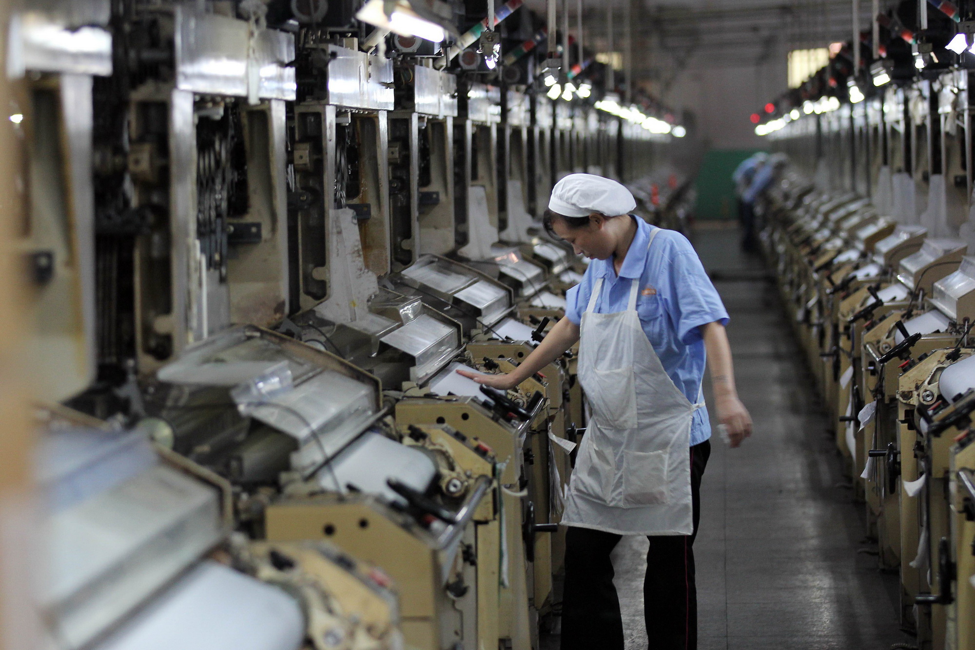 Công nhân giám sát dây chuyền máy dệt vải tại một nhà máy ở Jinjiang, tỉnh Phúc Kiến, miền đông nam Trung Quốc. (Nguồn: AFP/TTXVN)