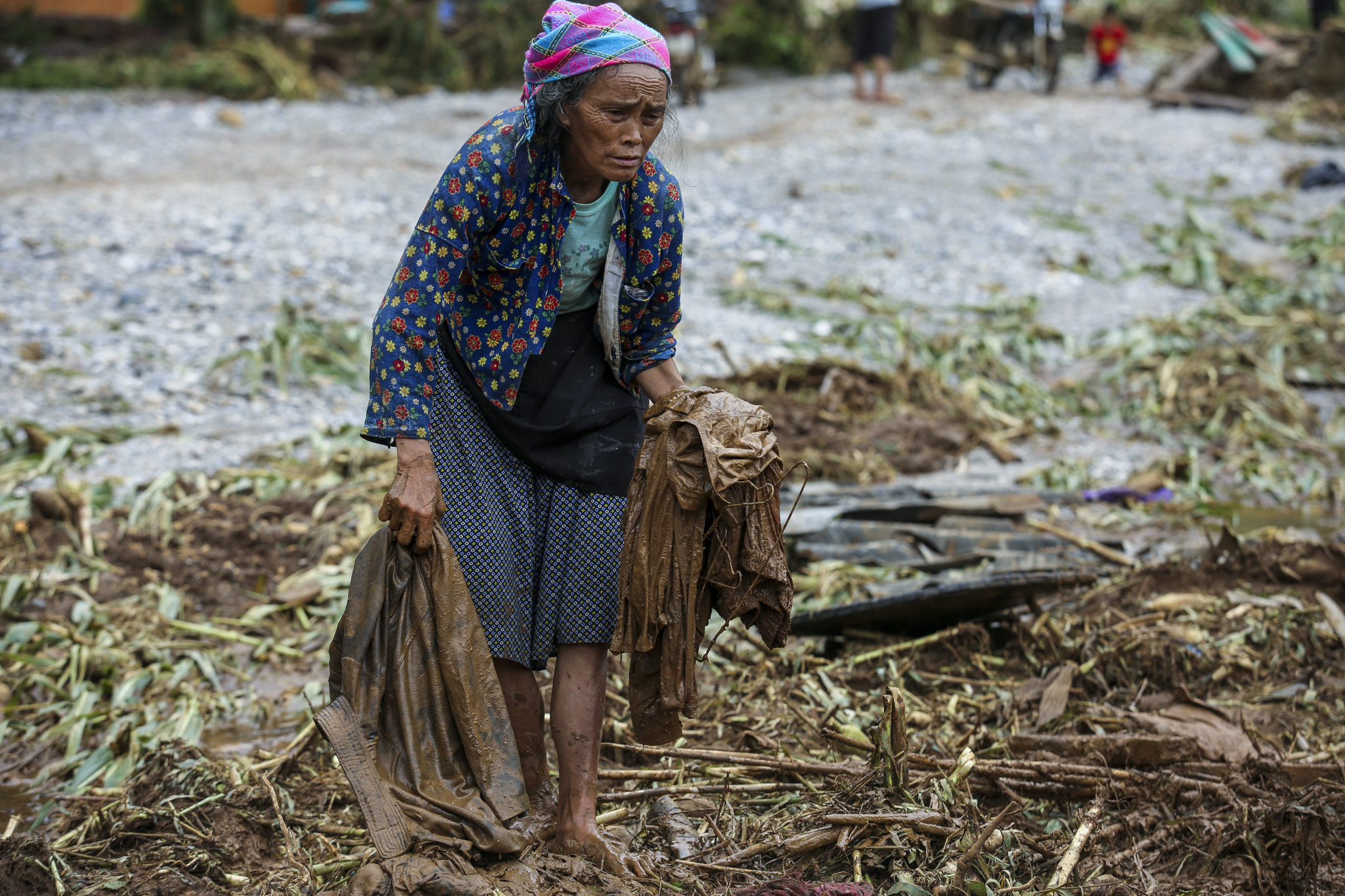 Những người dân thôn Tùng Nùn đang cố lần tìm những đồ vật còn sót lại bị chôn sâu dưới lớp lũ bùn. (Ảnh: Minh Sơn/Vietnam+)