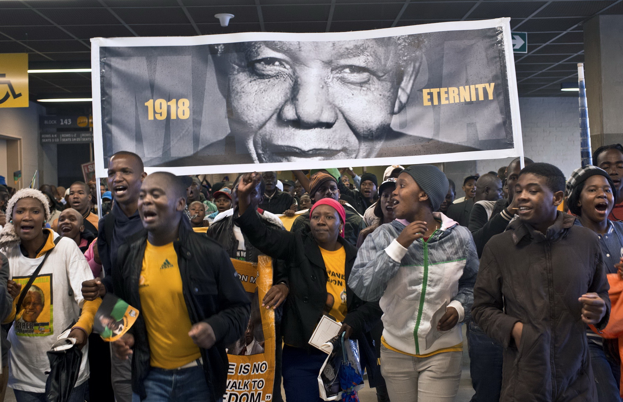 Người dân Nam Phi mang ảnh cố Tổng thống Nelson Mandela tới dự lễ tang của ông ngày 10/12/2013. (Nguồn: AFP/TTXVN)
