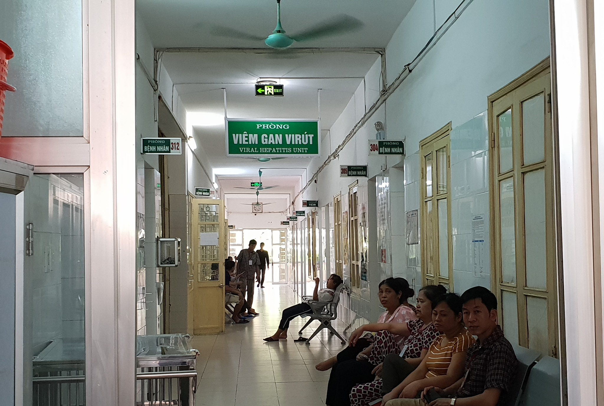 Người dân ngồi trước phòng điều trị cho bệnh nhân mắc bệnh viêm gan. (Ảnh: Thùy Giang/Vietnam+) 