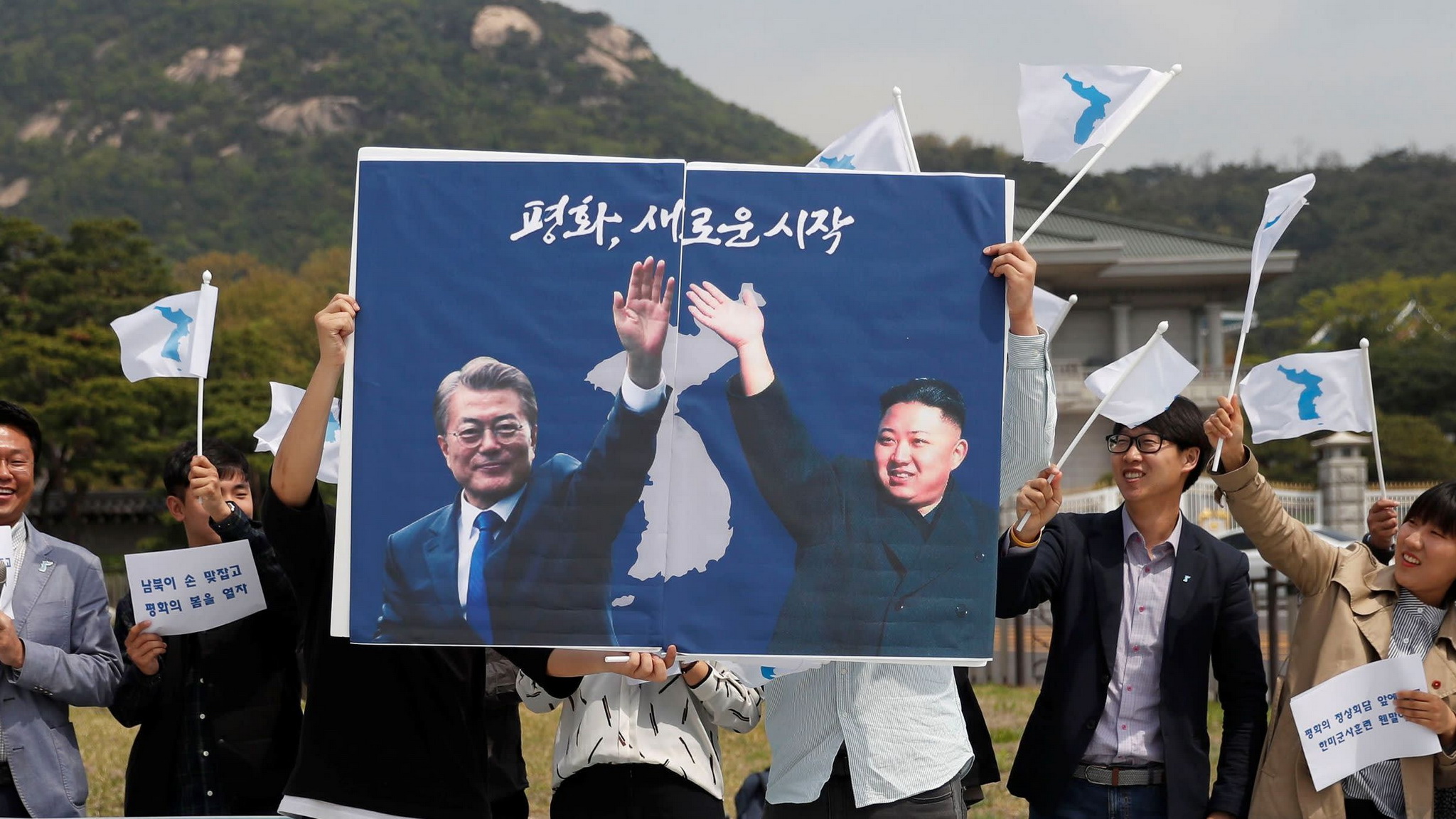 Các sinh viên giơ cao tấm poster có ảnh của nhà lãnh đạo Triều Tiên Kim Jong-un và Tổng thống Hàn Quốc Moon Jae-in. (Nguồn: Asia.nikkei.com)