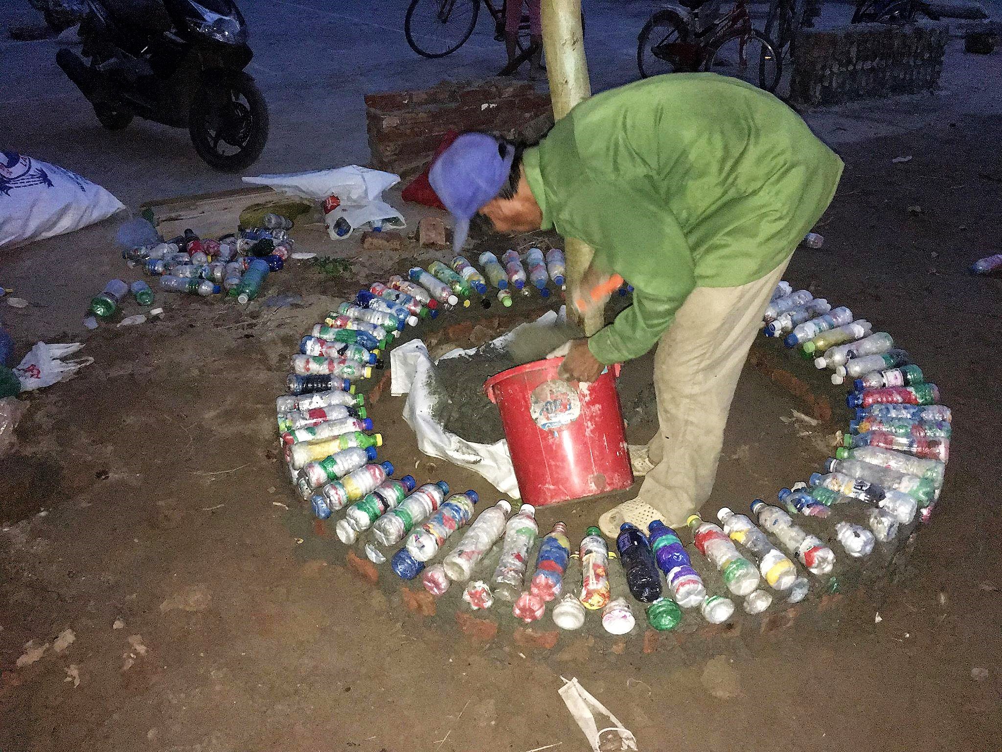 A man in Dong Anh district use ecobricks to build a tree fence. (Photo: VNA)