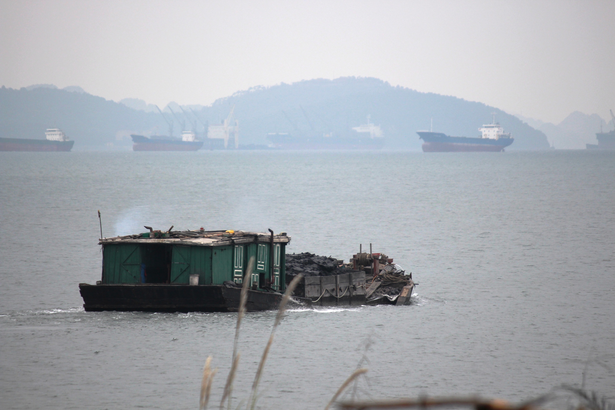Một chiếc tàu chở than rời khỏi khu vực “thiên đường than lậu” tại phường Cẩm Thịnh hướng ra biển đưa đi tiêu thụ. (Ảnh: P.V/Vietnam+)