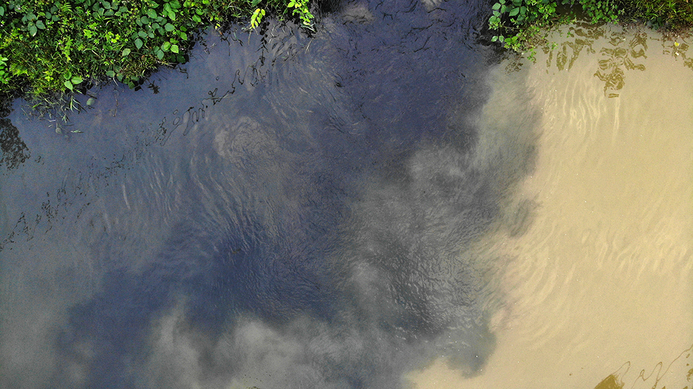 Nước tại con suối chia làm hai màu rõ rệt sau khi bị nghi nhiễm một lượng dầu lớn.