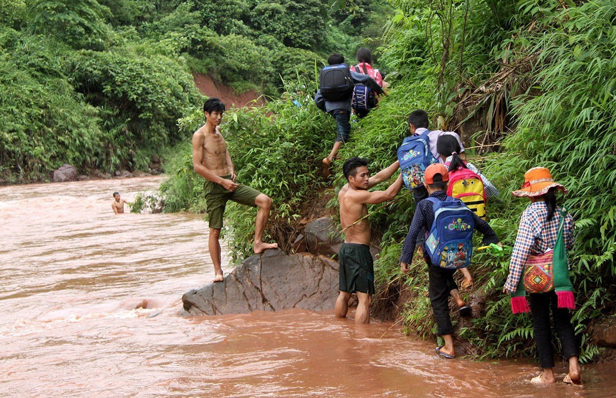 Ở nhiều địa phương của tỉnh Lai Châu, học sinh phải đi đò qua sông đến trường với sự giúp đỡ của giáo viên. (Ảnh: Việt Hoàng/TTXVN)
