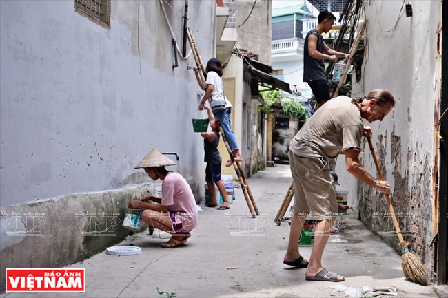                Paul y otros voluntarios quitan los anuncios pegados en paredes en Hanoi       