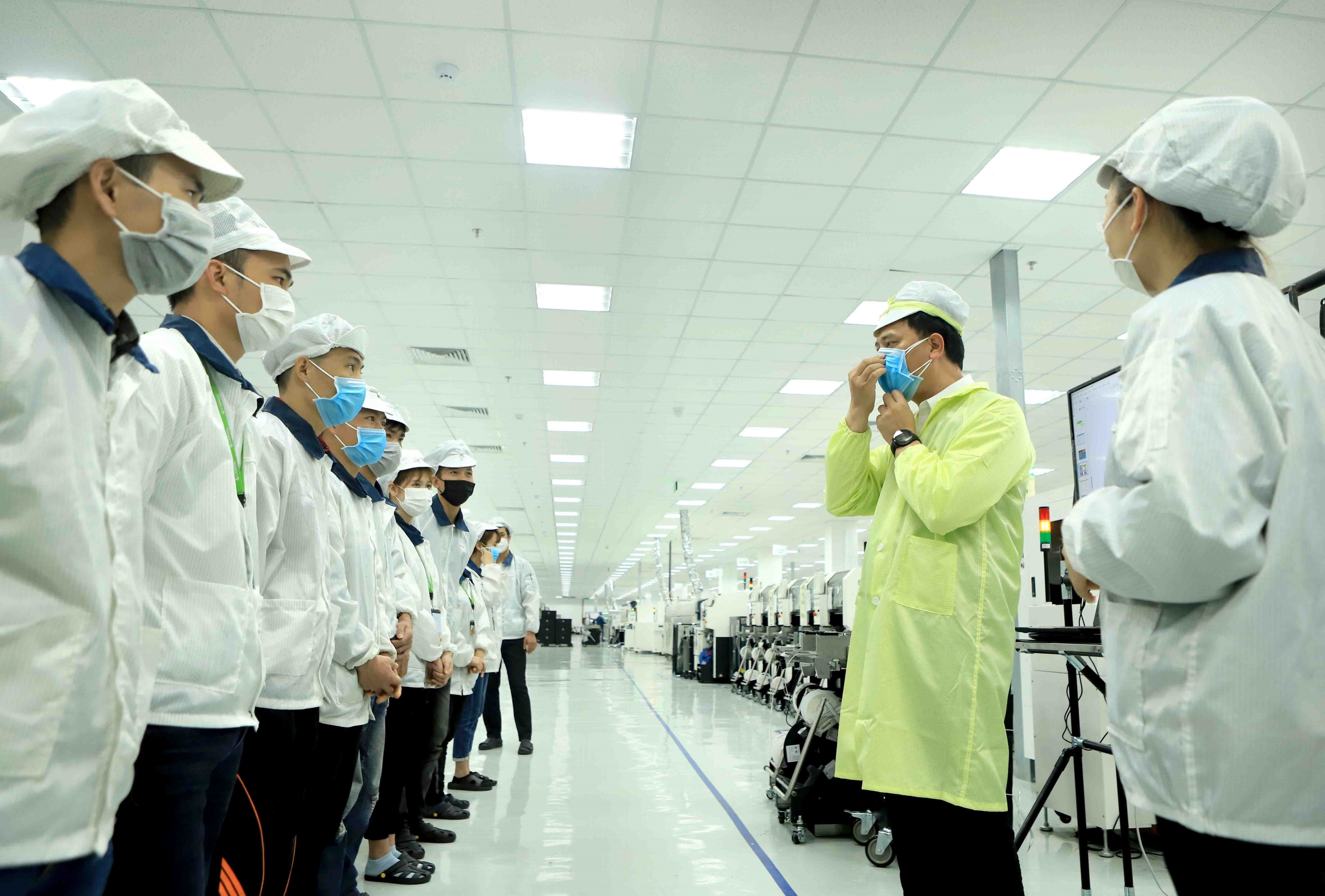 Công ty trách nhiệm hữu hạn Compal Việt Nam trong khu công nghiệp Bá Thiện 1 (huyện  Bình Xuyên) hướng dẫn cho công nhân đeo khẩu trang đúng cách để phòng  dịch COVID-19. (Ảnh: Hoàng Hùng/TTXVN)