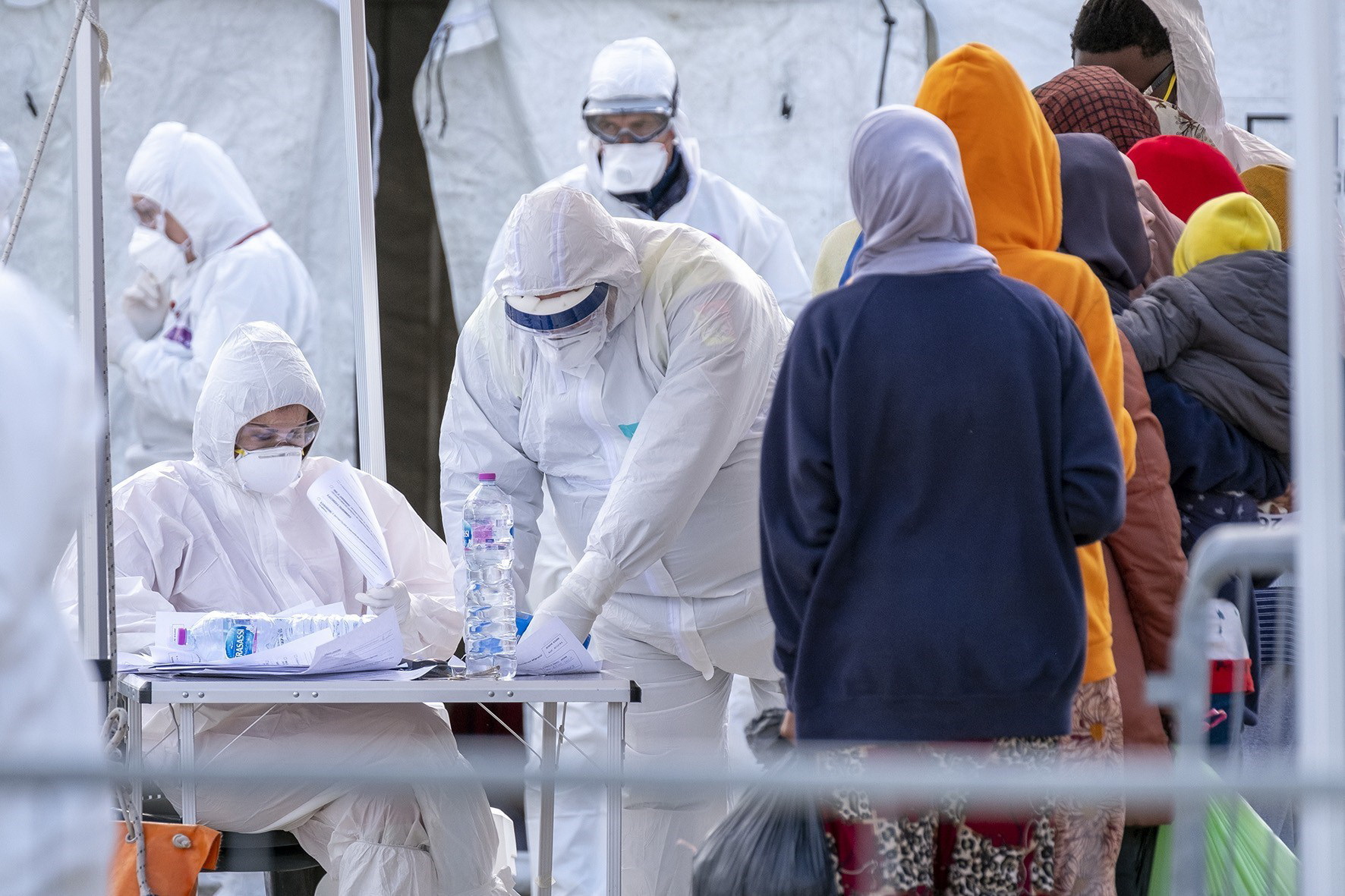 Nhân viên Hội Chữ thập đỏ Italy trong trang phục bảo hộ chống virus SARS-CoV-2  khi tiếp nhận người di cư được giải cứu trên Địa Trung Hải tại khu cảng ở  Messina, Sicily. (Ảnh: AFP/TTXVN)