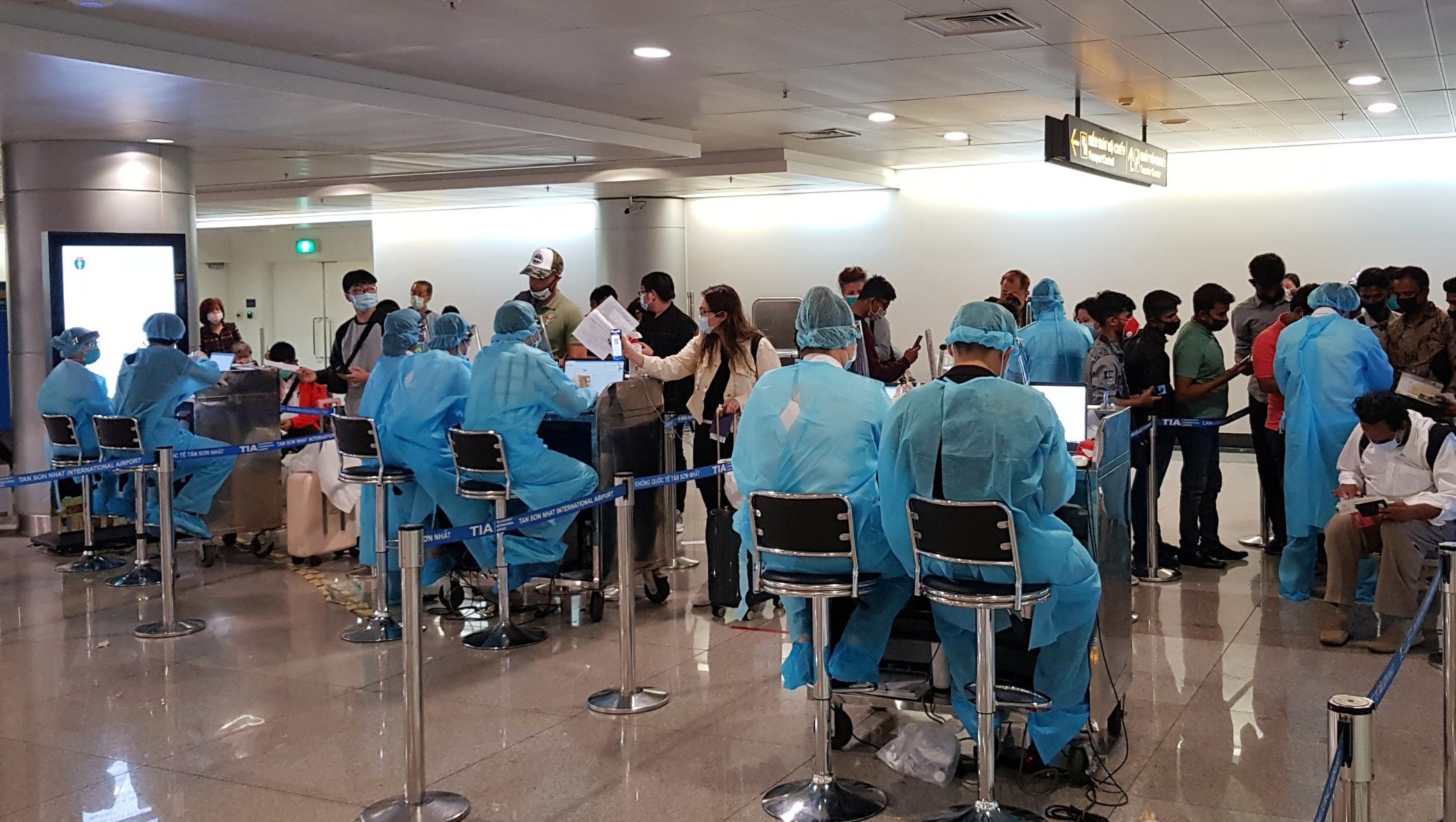 Nhân viên Trung tâm Kiểm dịch y tế quốc tế hướng dẫn hành khách  thực hiện tờ khai y tế trước khi làm thủ tục nhập cảnh tại sân bay Tân  Sơn Nhất Thành phố Hồ Chí Minh. (Nguồn: TTXVN phát)