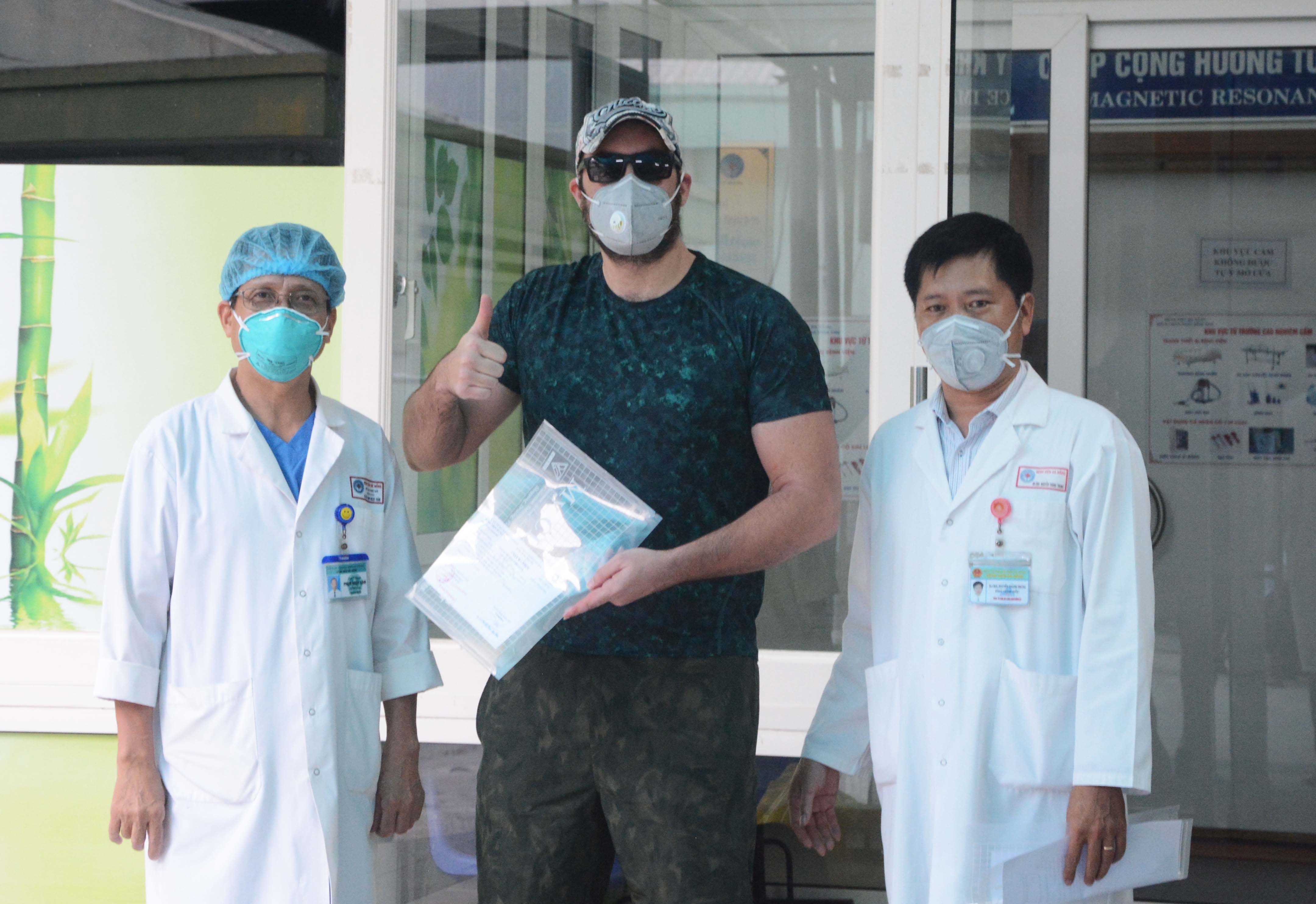 Các bác sỹ bệnh viện Đà Nẵng trao giấy chứng nhận khỏi bệnh cho bệnh nhân COVID-19 số 68, quốc tịch Mỹ, 41 tuổi. (Ảnh: Văn Dũng/TTXVN)