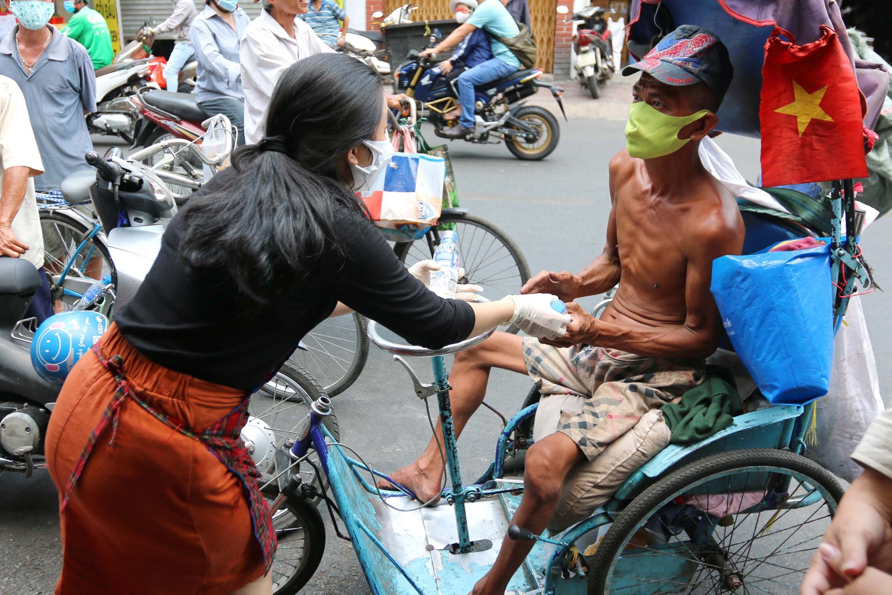 Chị Võ Thị Thùy Trang, chủ cửa hàng cơm chay Bình An trao từng phần cơm, quà tận tay người nghèo trong những ngày dịch COVID-19. (Ảnh: Thanh Vũ/TTXVN)
