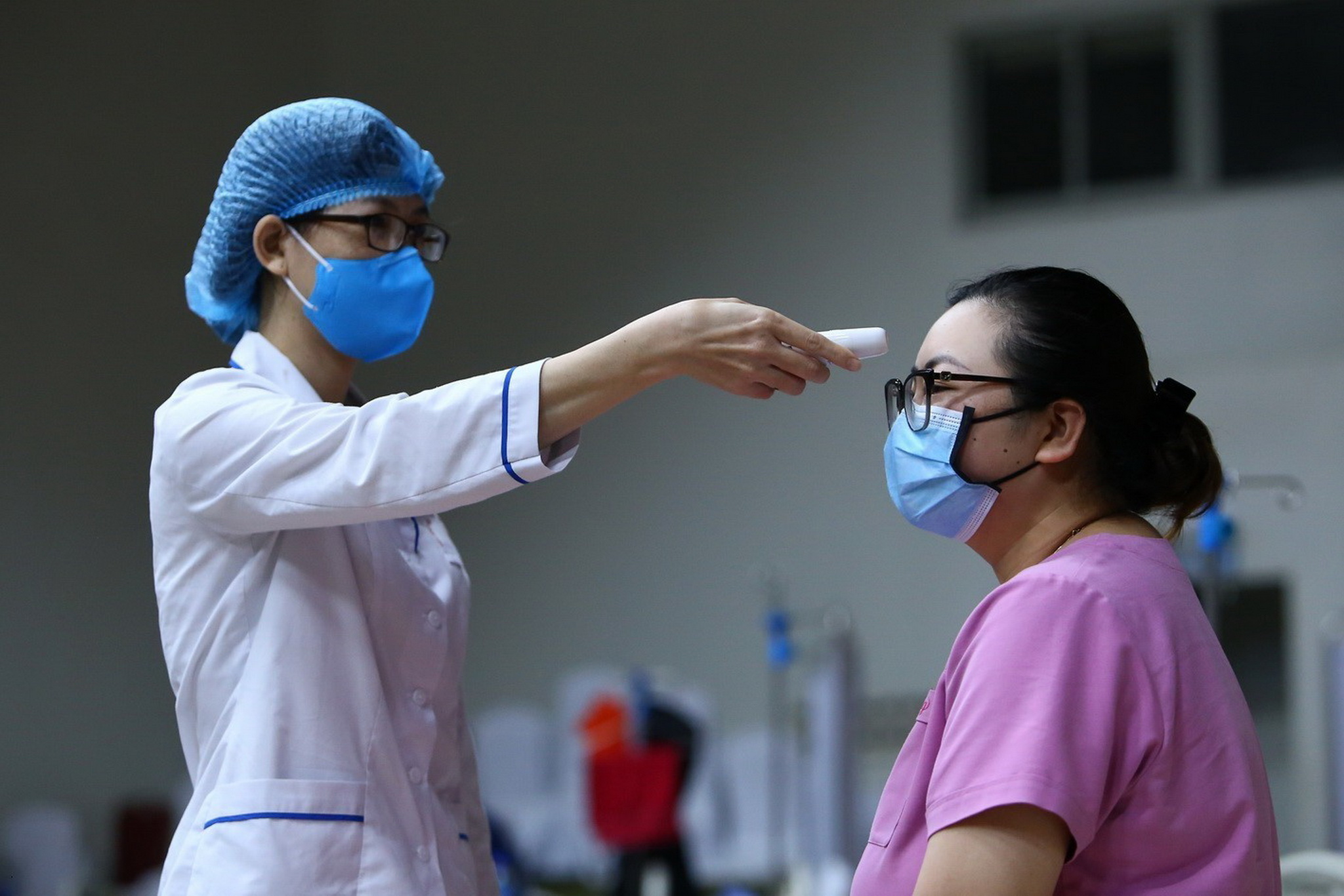 Kiểm tra thân nhiệt cho một người dân trong khu vực cách ly ở Viện Huyết học và Truyền máu Trung ương, Hà Nội. (Nguồn: TTXVN)