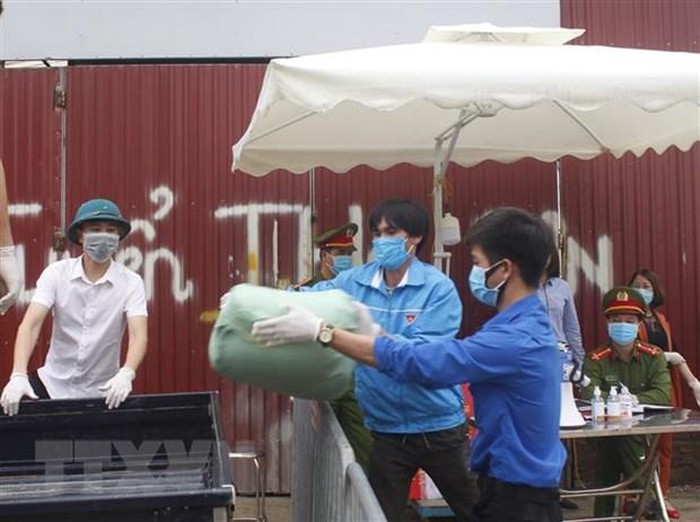 Lực lượng liên ngành khẩn trương vận chuyển hàng hóa đưa vào trong thôn Hạ Lôi. (Ảnh: Nguyễn Thắng/TTXVN)