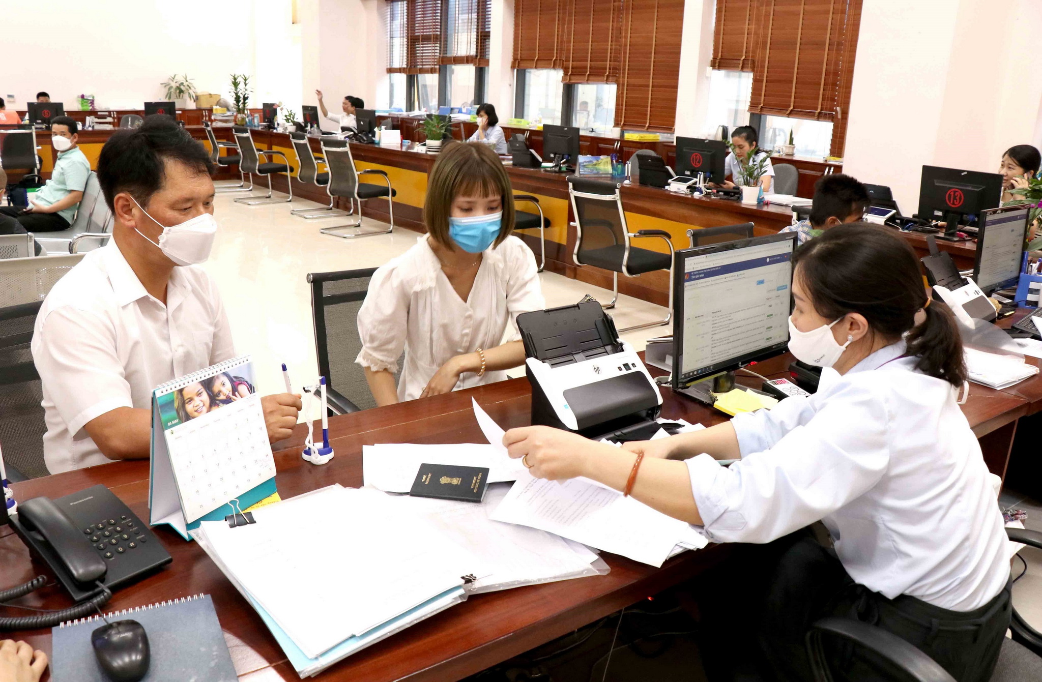 Cán bộ, nhân viên Trung tâm hành chính công tỉnh Bắc Ninh hướng dẫn người dân, doanh nghiệp giải quyết các thủ tục hành chính. (Ảnh: Đinh Văn Nhiều/TTXVN)