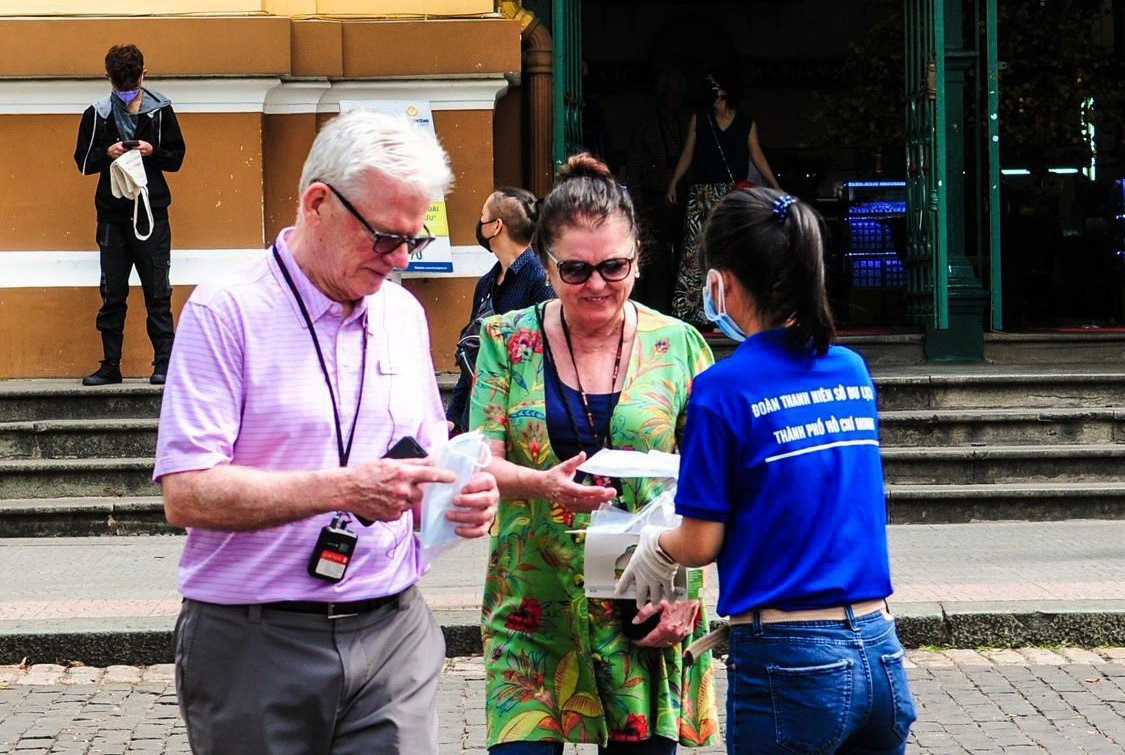 Nhân viên Sở Du lịch Thành phố Hồ Chí Minh phát khẩu trang miễn phí cho khách du lịch nước ngoài. (Ảnh: Đinh Hằng/TTXVN)