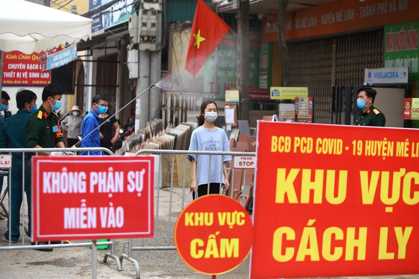An officer sprays disinfectant on a shipper of essential goods in the sealed-off zone in Ha Loi hamlet of Hanoi’s Me Linh district (Photo: VNA)