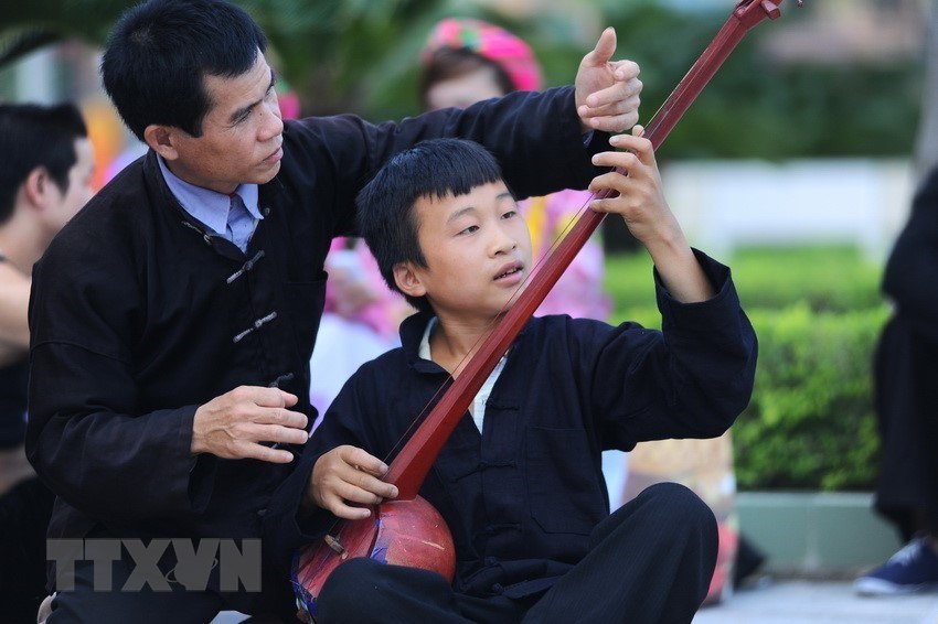 Nghệ nhân Hoàng Đức Thăng ( bên phải, bản Dâng, xã Cao Bồ, huyện Vị Xuyên, tỉnh Hà Giang) truyền dạy cách sử dụng đàn tính cho thế hệ trẻ. (Ảnh: Minh Đức/TTXVN)