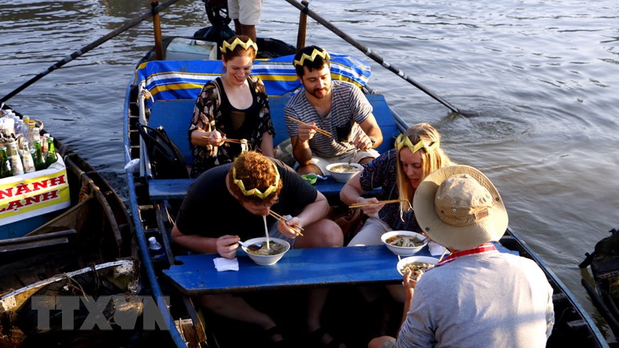 Foreign tourists enjoy their breakfast of hu tieu (noodle soup), a famous dish at the Cai Rang floating market. (Photo: VNA)