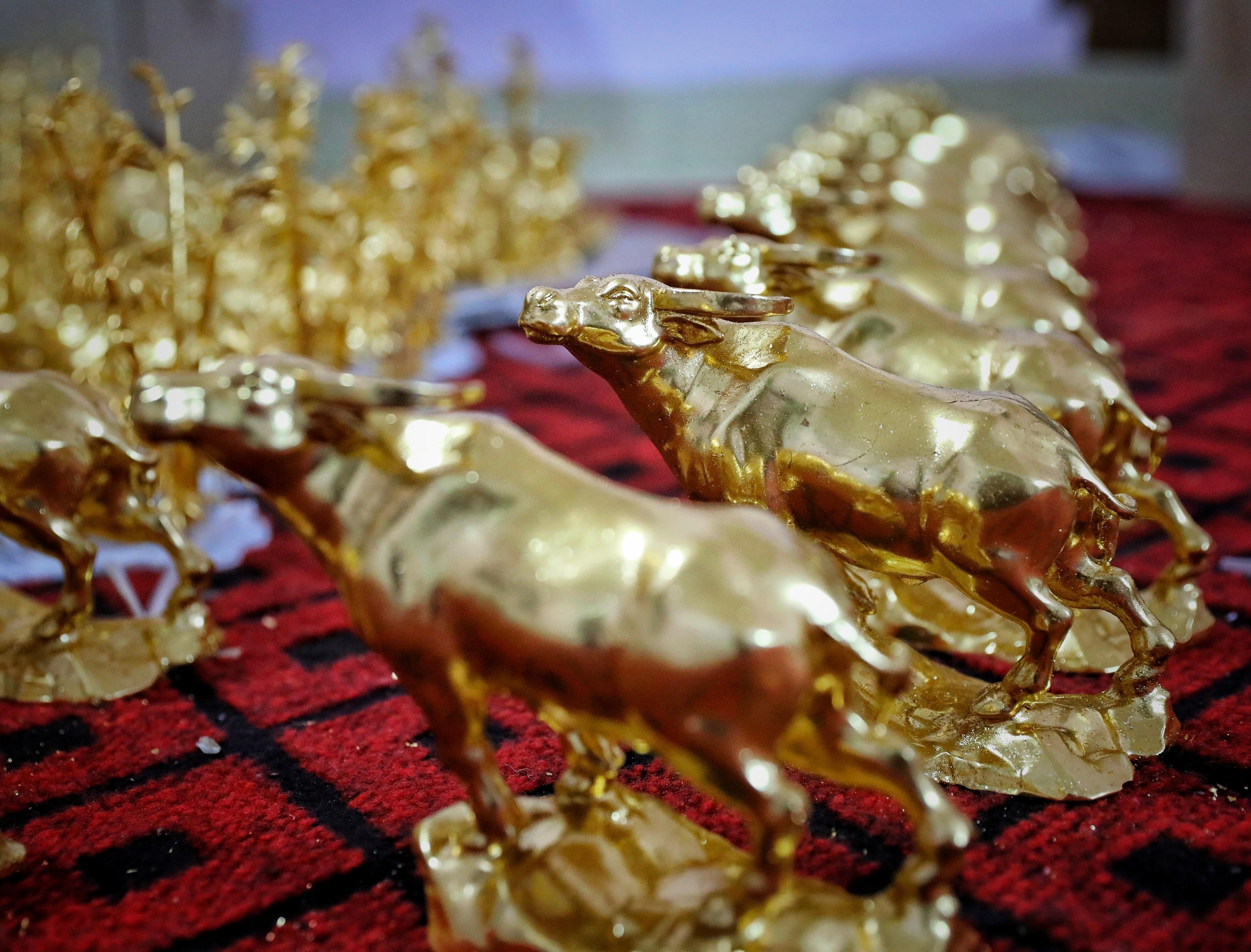 Gia đình nghệ nhân Nguyễn Anh Chung thếp vàng lên tượng trâu vàng cho khách hàng. (Ảnh: Danh Lam/TTXVN)