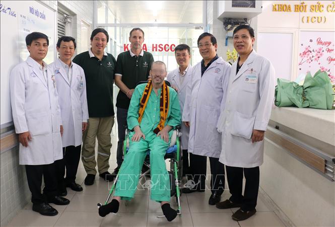 Patient 91 (sitting) in a photo with doctors and representative of the UK Consulate in HCM City on the day he is discharged from hospital (Photo: VNA) 